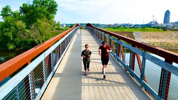 Two people are walking on a bridge.